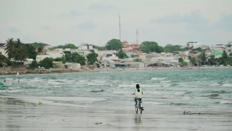 little girl rides bicycle on vietnamese seashore of mui ne beach, near fisherman village