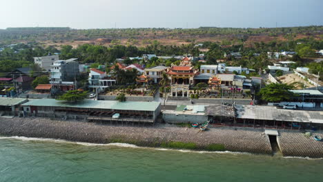 Buddhist-temple-on-coastal-road-in-Ham-Tien,-Vietnam,-aerial-view