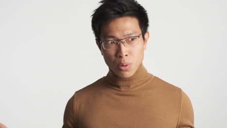 안경을 쓴 아시아인 남자가 혼란스러워 보입니다.