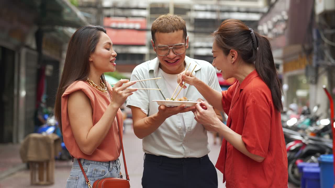 4k 그룹의 아시아인 친구들이 차이나타운에서 함께 고 거리 음식을 함께 먹고 있습니다.