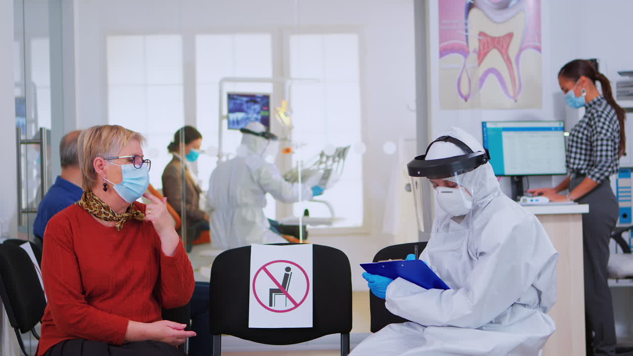 검사 전 노인 여성 과 대화 하는 얼굴 방패 를 착용 한 치과 의사