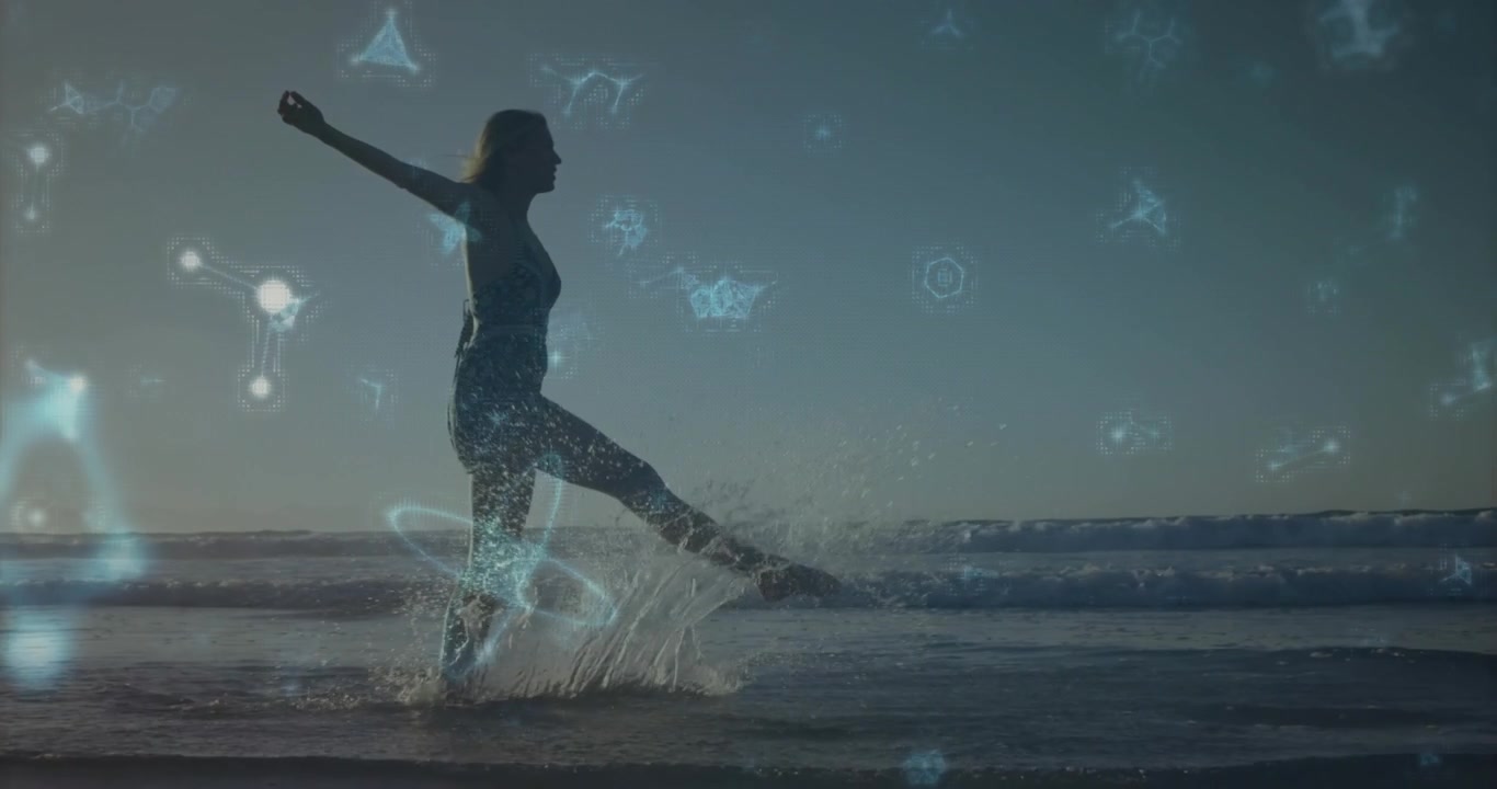 Donna di mezza età che entra tra le onde e calcia l'acqua, attivando una sovrapposizione molecolare blu per la salute