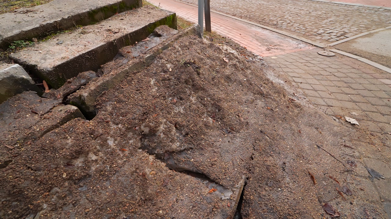 Dirty melting snowbank piled beside concrete steps and a sidewalk, mixed with sand and road salt after winter—urban thaw grime, spring cleanup, and street maintenance concept.