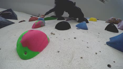 close up of an indoor climbing gym wall full of different colour holds seen from below-2