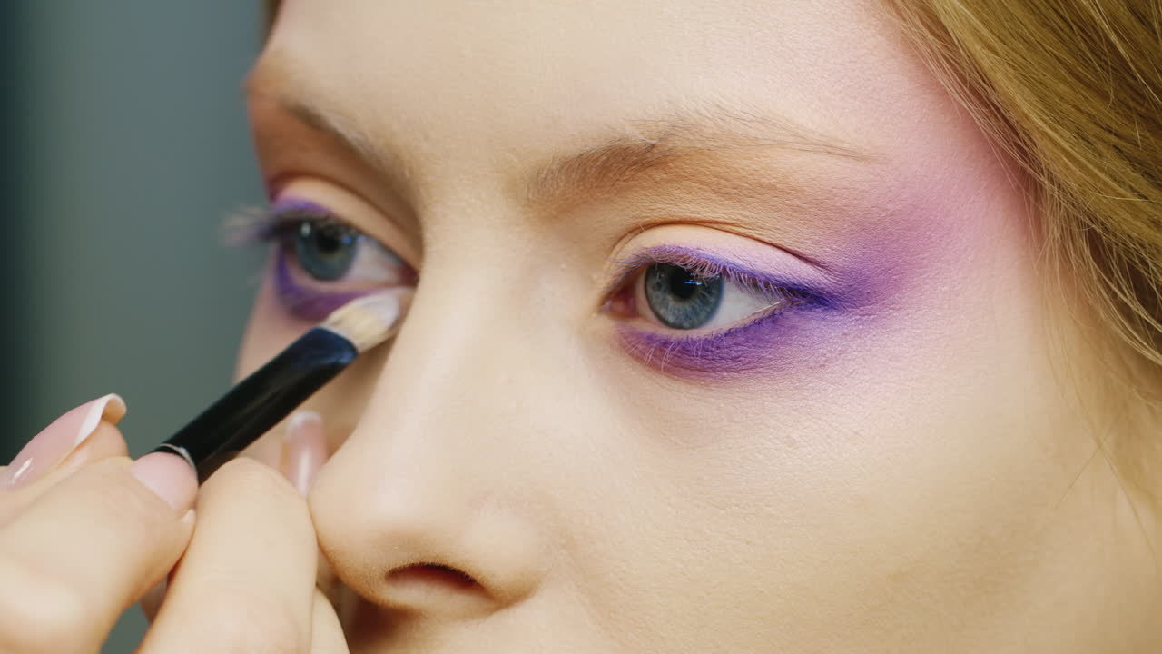 aplicar maquillaje en un hermoso ojo femenino de color azul