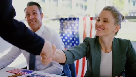 businesswomen shaking hands with each other while checking in at political campaign table 4k