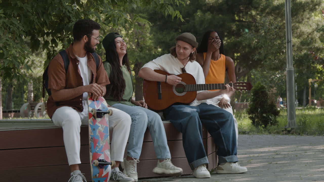 Diverse group of friends playing guitar and socializing in a park