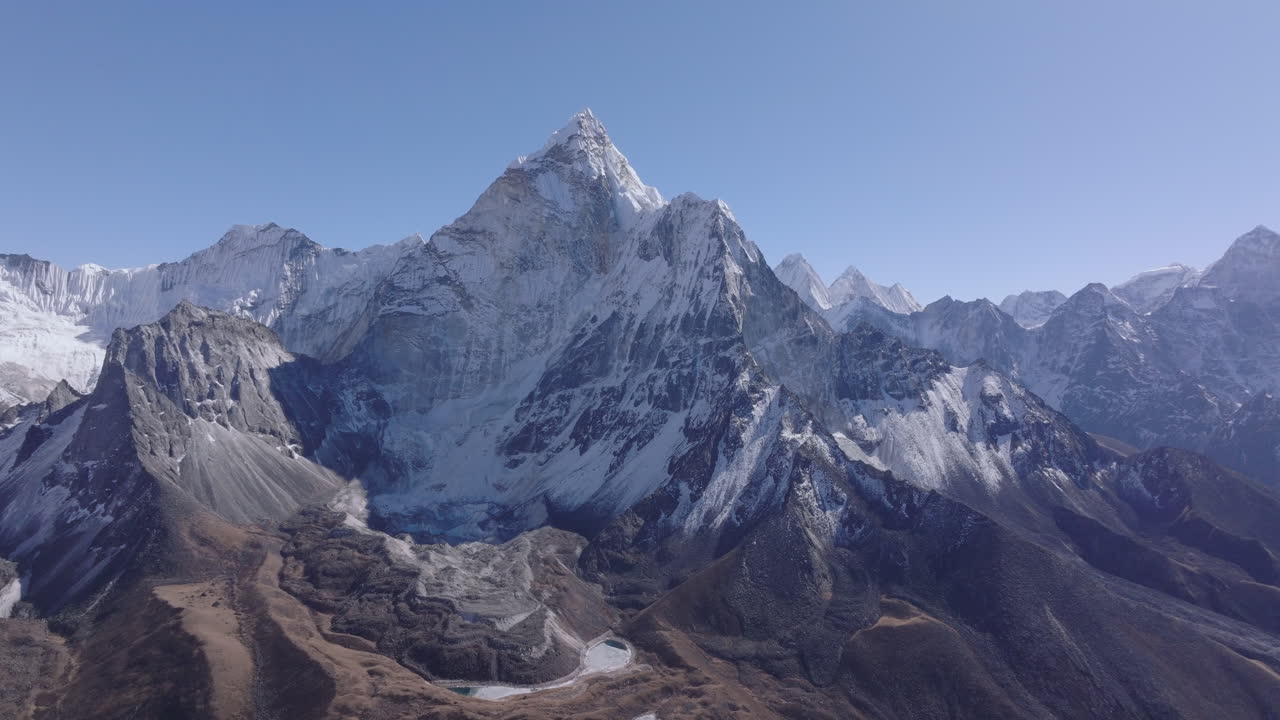 Aerial gliding drone shot of Ama Dablam in Nepal’s Everest region, showcasing the Himalayan mountain view. Reduced snow cover on surrounding peaks highlights visible environmental change at high altit
