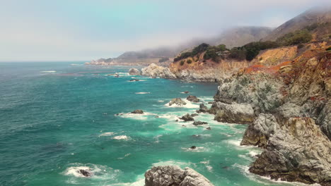 drone aerial flight over powerful crashing waves onto sharp rocks