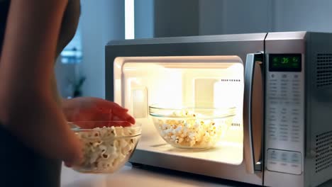 woman making popcorn in a microwave