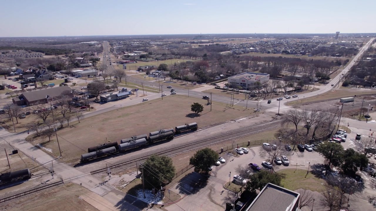 4K drone push-in footage of railroad tracks in downtown Midlothian, Texas, highlighting transportation infrastructure, urban development, and North Texas city scenery.