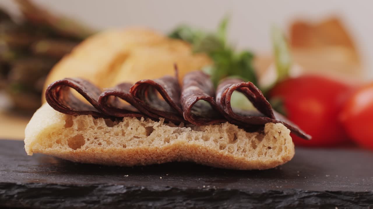 black bull sausage ham, tongue pork dry-cured sausage on a black background, traditional spanish delicatessen food, close up.