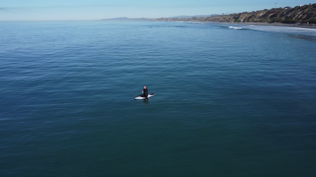 un hermoso disparo aéreo de drones, drones rastreando a un hombre cenando en el océano cerca de la playa, playa estatal de carlsbad - california