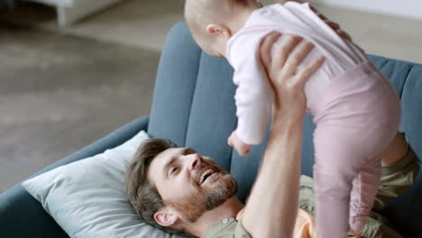 father playing with his baby daughter on a couch