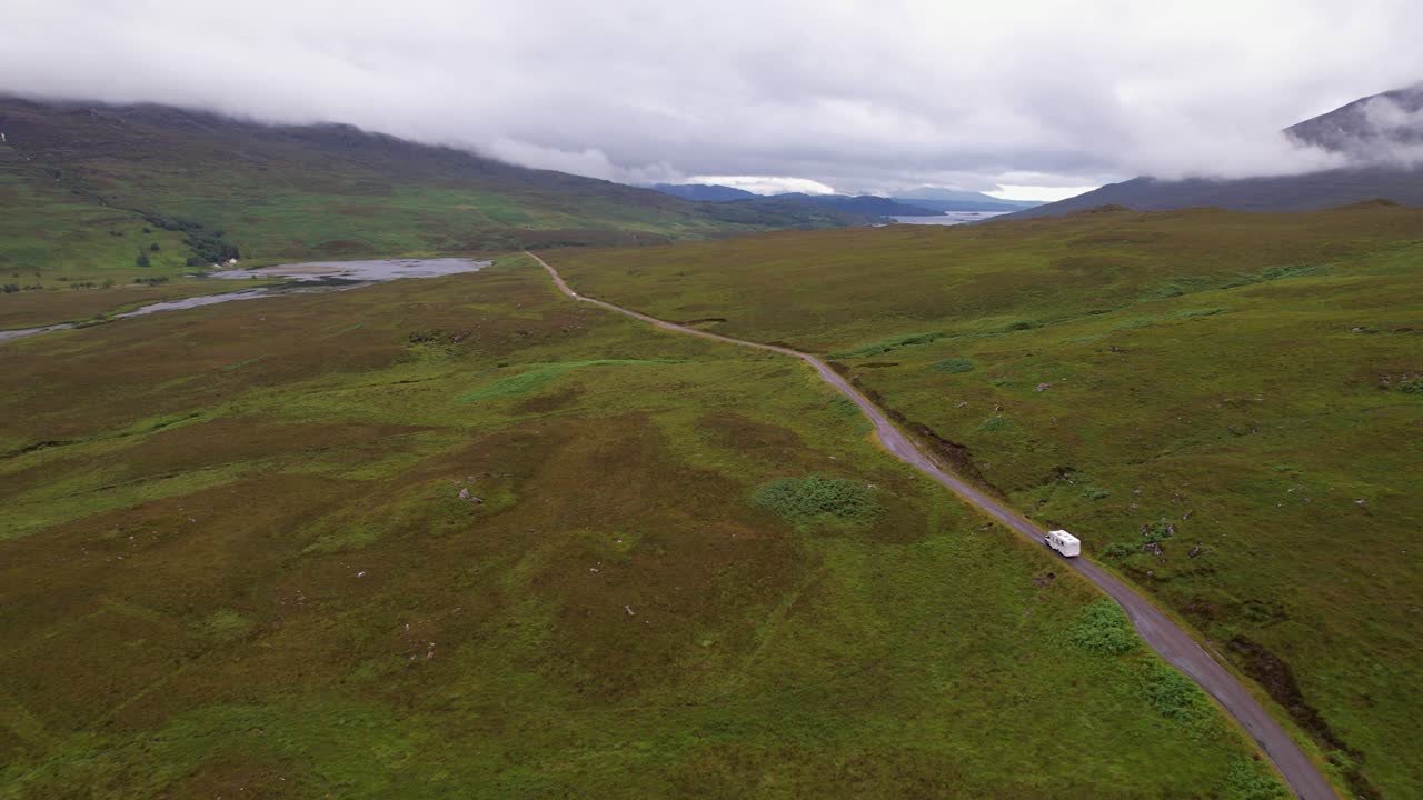 un camino solitario se extiende a través de las vastas tierras altas verdes de escocia, evocando la soledad