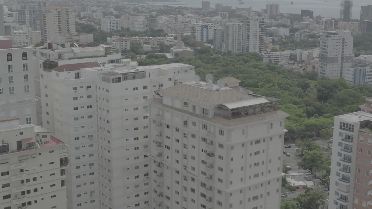 Santo Domingo, Dominican Republic – June 22, 2025: Aerial drone footage capturing a large modern building with the city skyline of Santo Domingo in the background, 4k raw color video.
