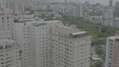 santo domingo, dominican republic – june 22, 2025: aerial drone footage capturing a large modern building with the city skyline of santo domingo in the background, 4k raw color video.