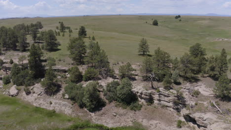 aerial views of a grassy plane heading to a beautiful rock formation in palmer lake colorado