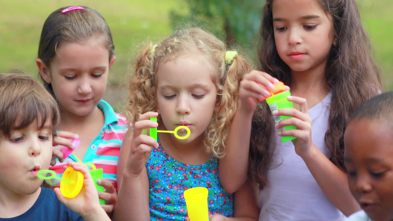 niños jugando con la varita de burbujas en el parque