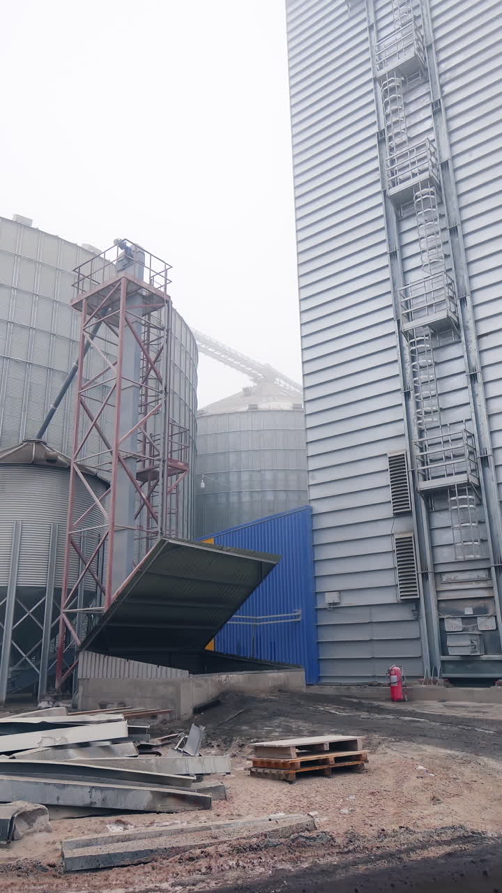 Metal tanks of elevator. Grain-drying complex outdoors. Commercial grain silos on sky background.. Vertical video
