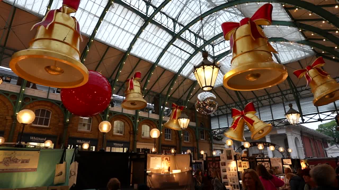 Christmas decorations with large bells and ornaments hanging in Covent Garden's Apple Market, London