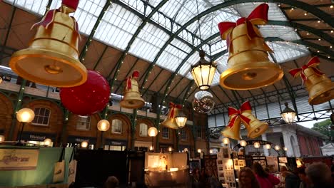 christmas decorations with large bells and ornaments hanging in covent garden's apple market, london