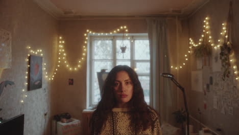 portrait of young beautiful woman in cozy room with string lights