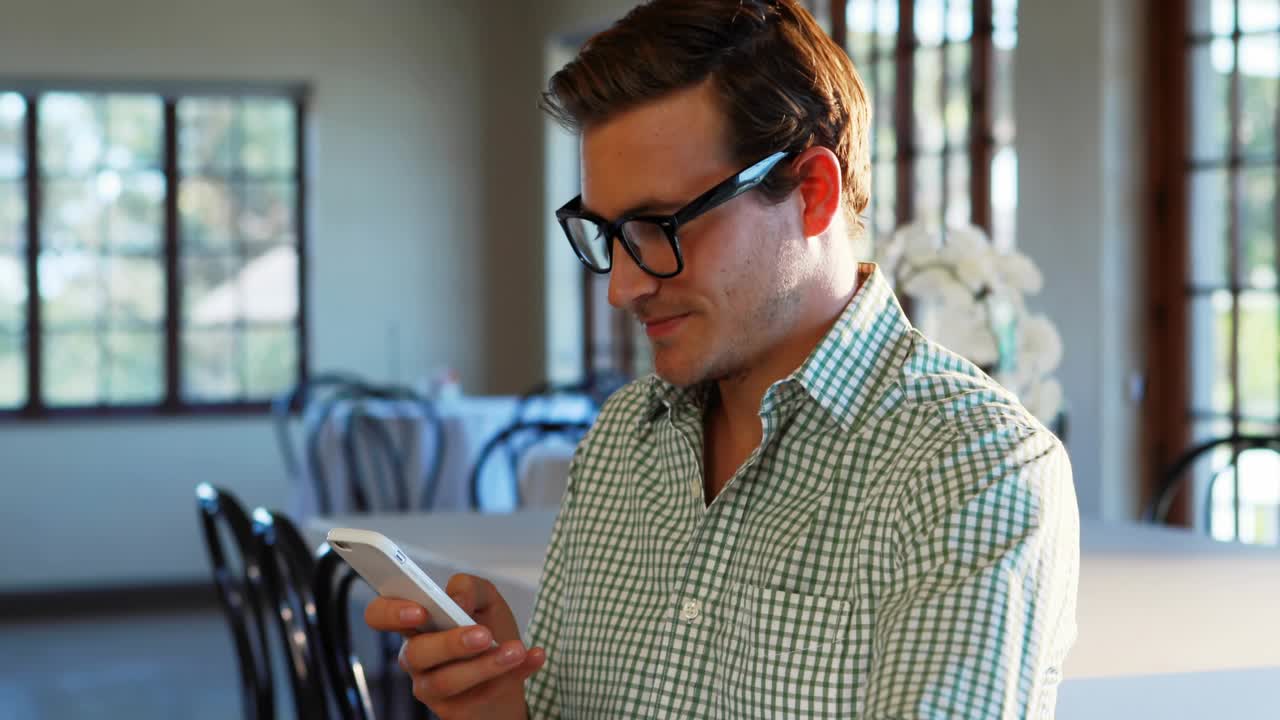 Man holding phone at table, tapping while notifications appearing near face, tracking social media
