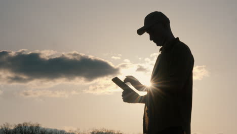 silhouette of a person using a tablet at sunset