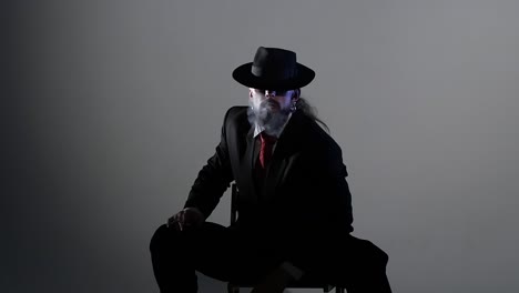 man in suit and fedora smoking with dramatic lighting