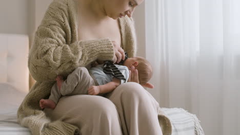 loving young mother breastfeeding her newborn baby while sitting on the bed at home 4