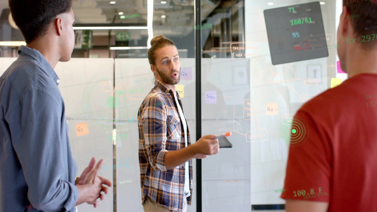 Vertical video: Office lead turning, pointing at notes on glass and display, inviting brainstorming