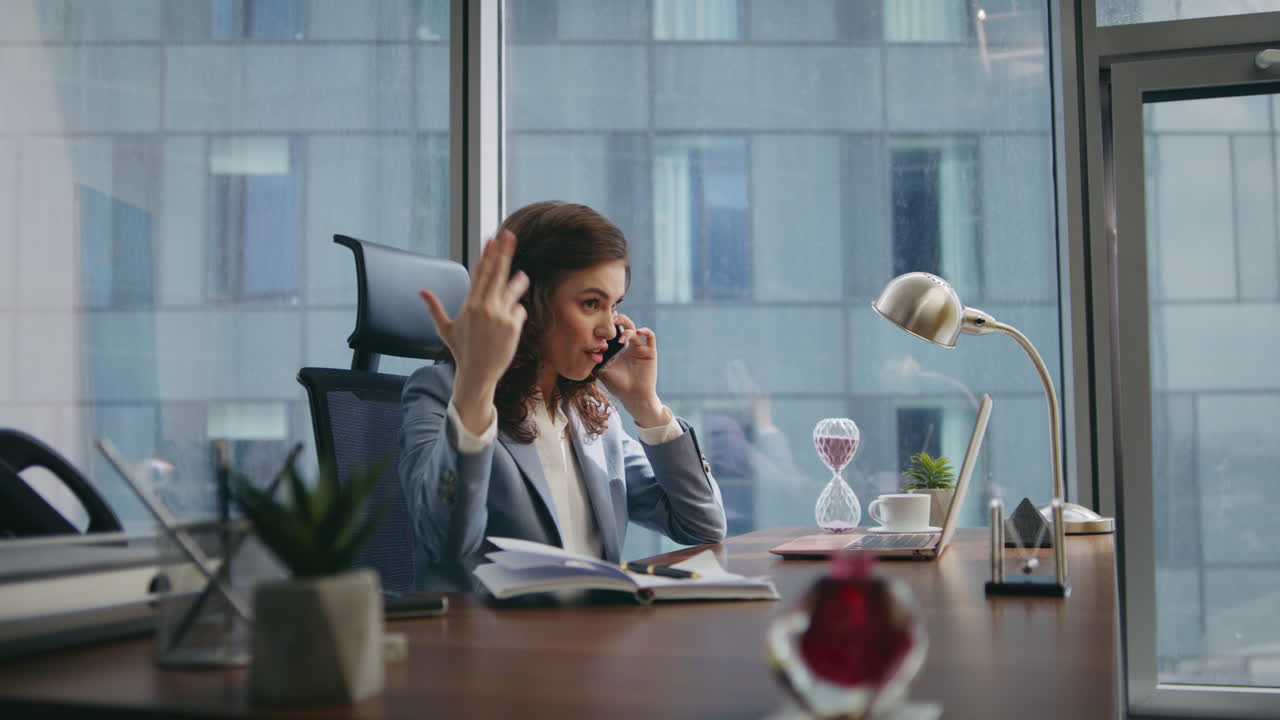 Nærbillede af en følelsesladet medarbejder, der råber i telefonen ved kontorbordet. Kvinde råber i telefonen.