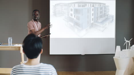 hombre afroamericano presentando un proyecto arquitectónico en una conferencia