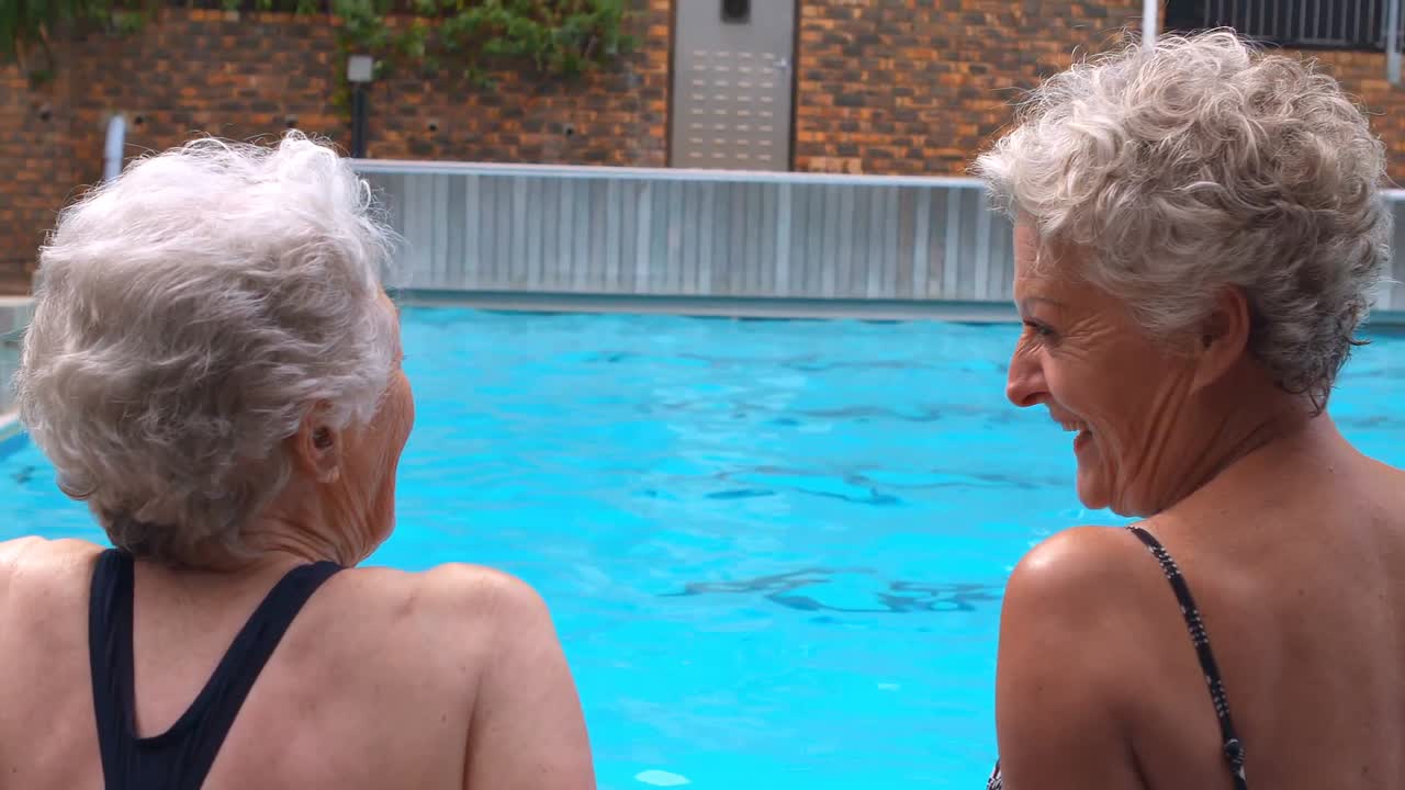 Due donne anziane sedute insieme a bordo piscina