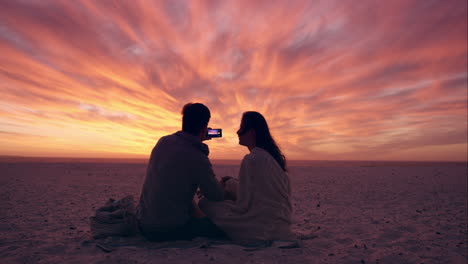 Feliz-Pareja-Romántica-Tomando-Fotografías-De-La-Puesta-De-Sol-Usando-La-Cámara-De-Un-Teléfono-Móvil-En-Un-Dragón-Rojo