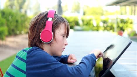 A-young-boy-attempts-to-learn-remotely-on-his-laptop-and-headphones-over-distance-learning-due-to-the-COVID-19-Corona-virus-outbreak