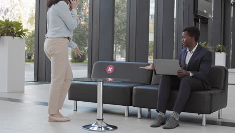 two businesspeople sitting on couch in business center hall