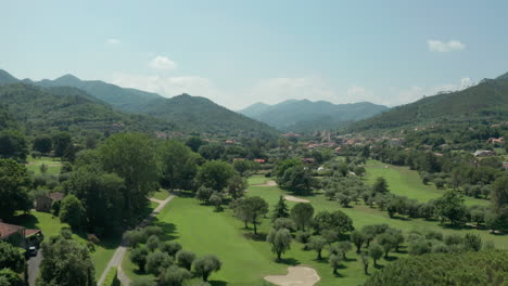 Levantamiento-Aéreo-Sobre-El-Pintoresco-Parque-De-Golf-En-El-Paisaje-Montañoso-Del-Norte-De-Italia