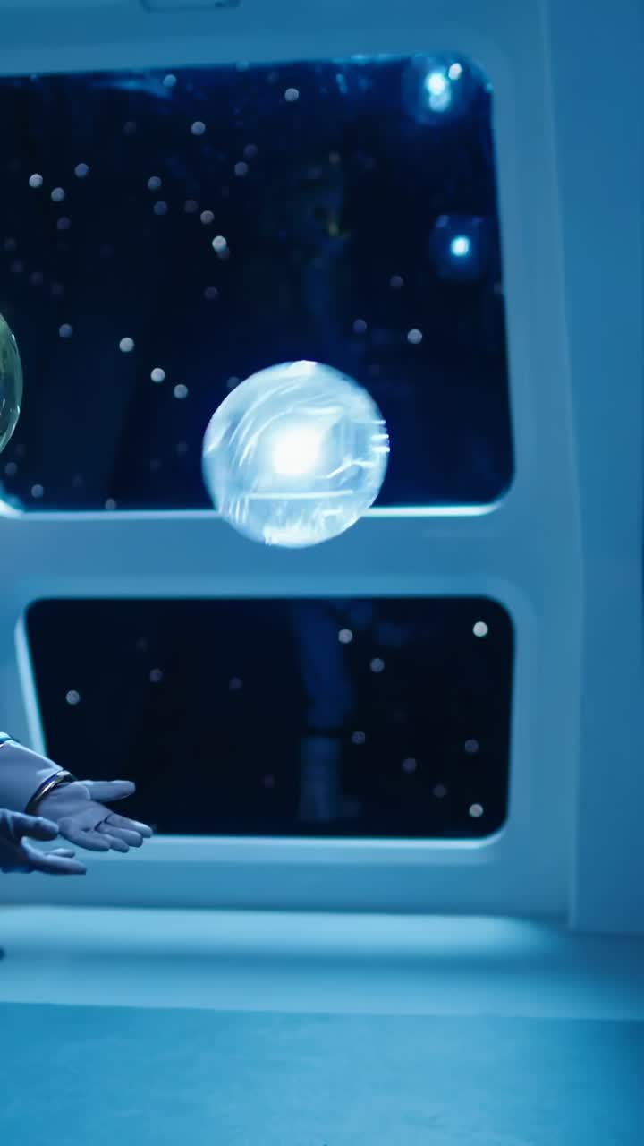 Vertical video: Detaching lit orb drifting in cabin, suited crew reaching nudging boots to catch