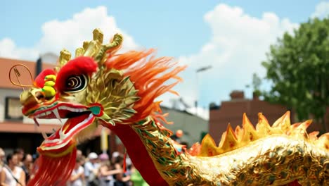golden chinese dragon celebrating chinese new year, parading vibrantly through the street in front of a crowd of excited, blurred people on a sunny summer day