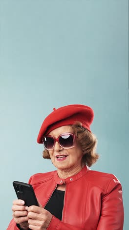 stylish senior woman in red fashion using smartphone