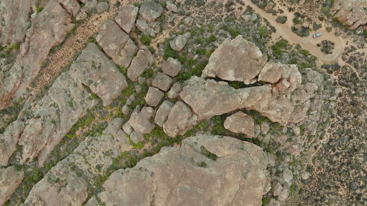 el dron vuela a vista de pájaro sobre el paisaje desértico y las formaciones rocosas en el área desértica de cederberg en sudáfrica sobre una carretera vacía en el desierto - el dron gira ligeramente hacia arriba
