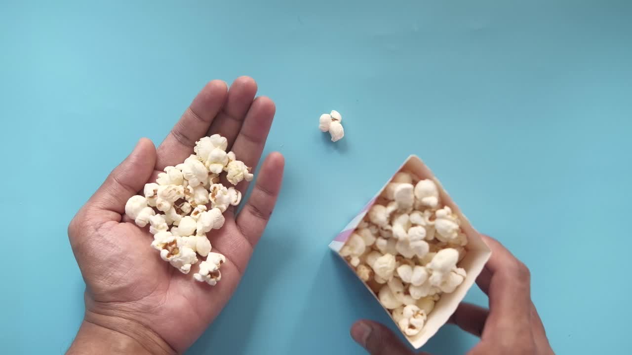 palomitas de maíz en las manos y en el recipiente