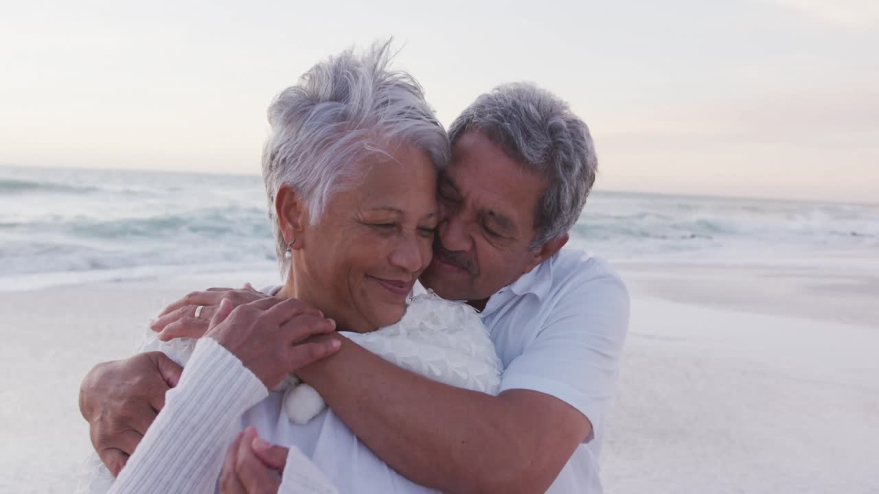 feliz hispano recién casado pareja de ancianos abrazándose en la playa al atardecer