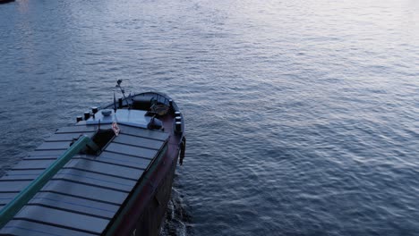 vista inclinada de arriba hacia abajo de un barco navegando por un canal durante la puesta de sol