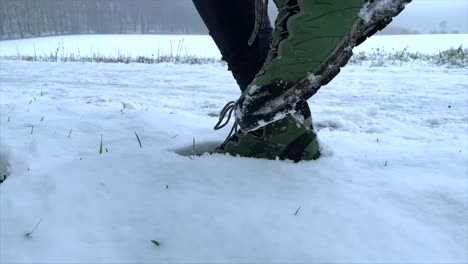 Excursionista-Con-Botas-De-Senderismo-Estampando-En-Nieve-Suave-Y-Profunda-Con-Un-Tallo-De-Hierba-Sobresaliente-Durante-El-Invierno