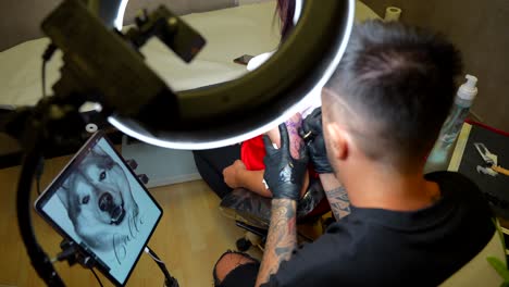 tattoo artist applying husky tattoo on woman's arm