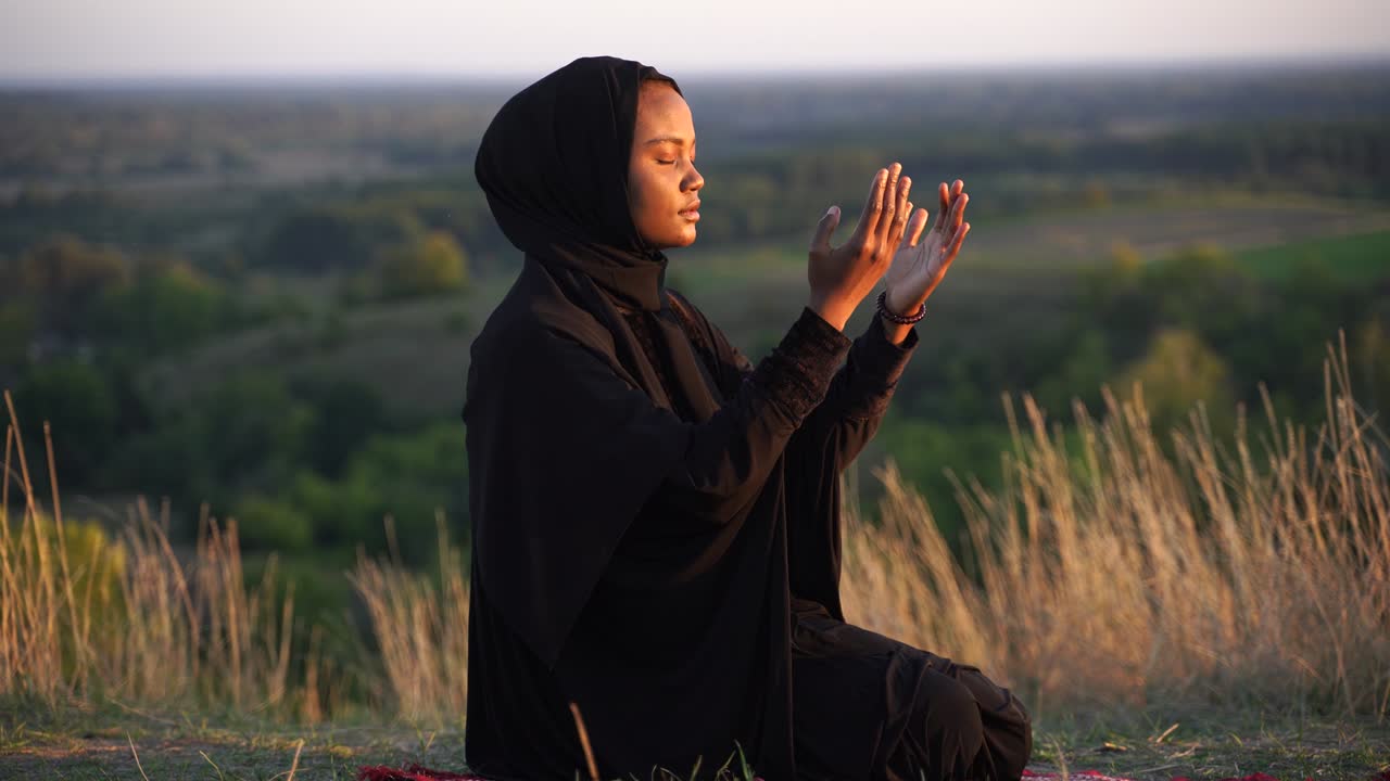 Donna musulmana nera in abito seduto sul tappeto. Solat tradizionale preghiera a dio.