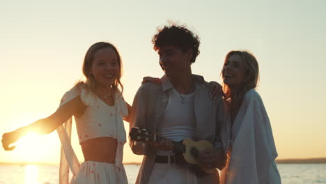 amigos tocando el ukulele en la playa del atardecer.